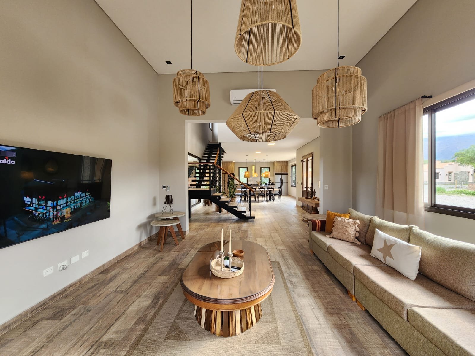 Living comedor con luz cálida y detalles en madera y rattan — proyecto Ca La Estancia, por Luciana González Anderson, en Cafayate